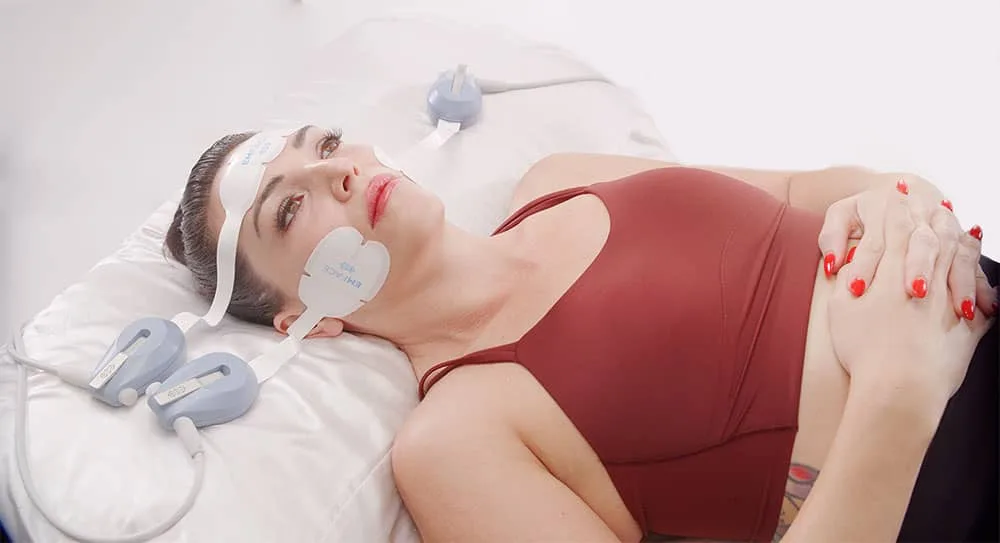 Woman lying down with facial applicators in place at our Clanwilliam Square clinic, EMface facial toning Dublin